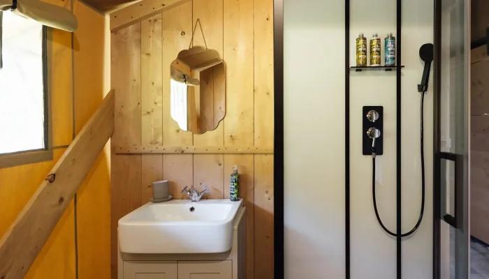 Indoor bathroom at Lime Kiln Lodge with toilet, sink and waterfall shower